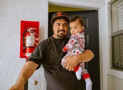 A dad holding his son at his frontdoor.