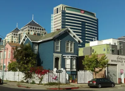 House at the corner of the street with a building in the background.