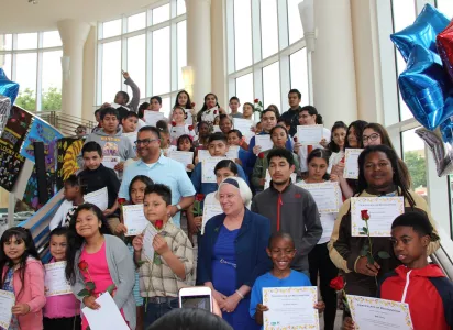 Students show certificates on the stairway.